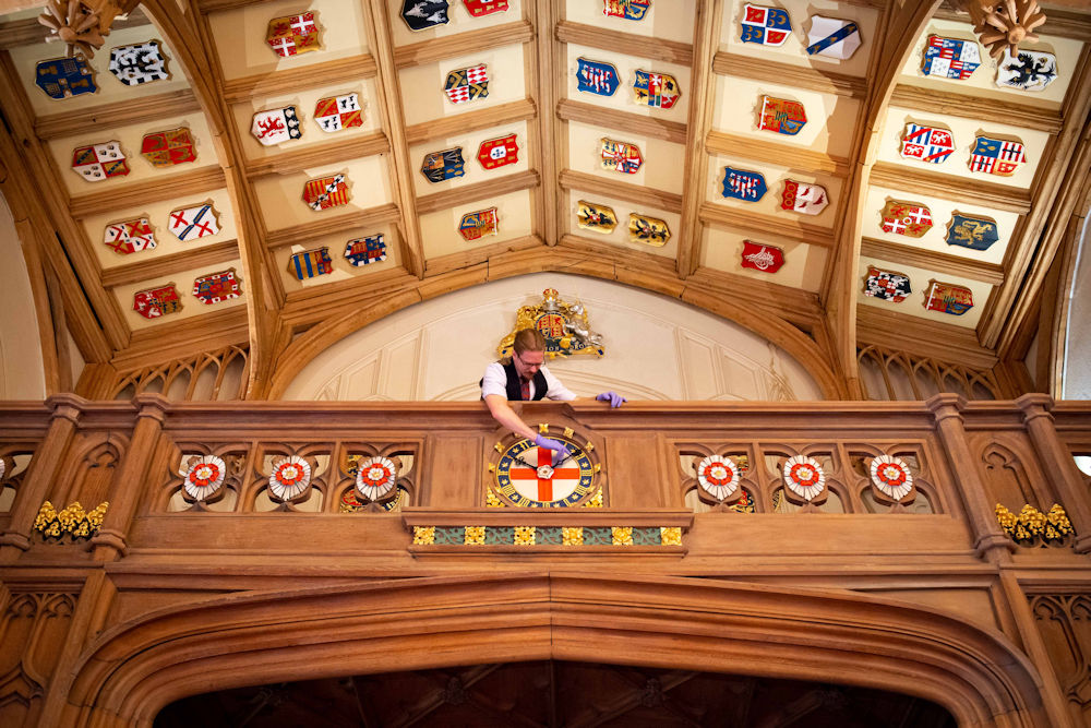 A Horological Conservator adjusts the gallery clock in St George’s Hall at Windsor Castle.